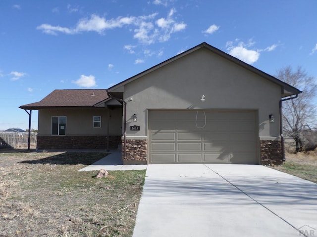 ranch-style home featuring stucco siding, driveway, stone siding, fence, and a garage