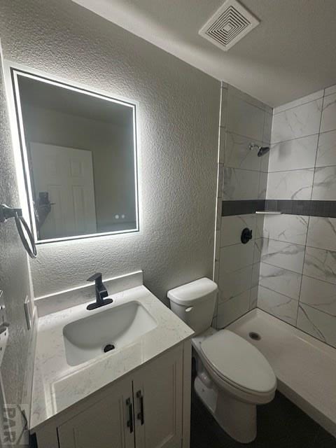 662 S Bayfield Ave, Pueblo West, CO 81007 - full bath featuring a textured wall, vanity, toilet, and a tile shower