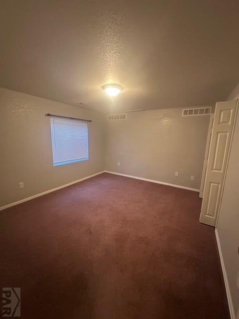 662 S Bayfield Ave, Pueblo West, CO 81007 - spare room featuring baseboards, dark colored carpet, and a textured ceiling