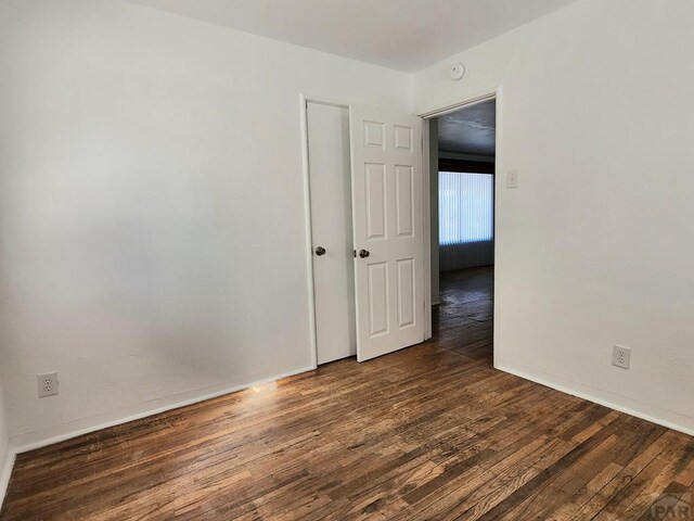 unfurnished room with dark wood-type flooring and baseboards