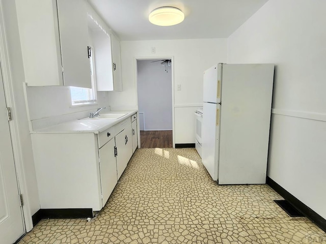 kitchen featuring white appliances, a sink, white cabinets, light countertops, and light floors