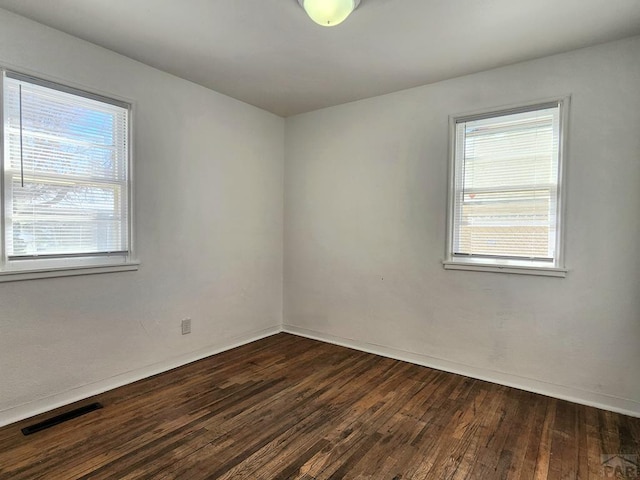 unfurnished room with visible vents and dark wood finished floors