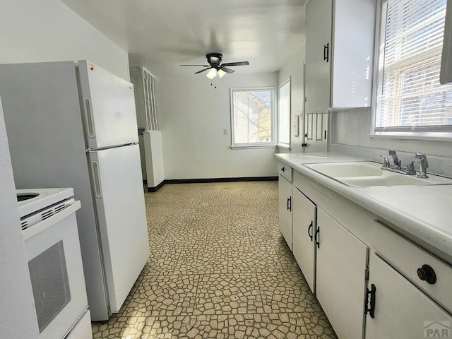 kitchen with light countertops, white range with electric cooktop, a sink, and white cabinets