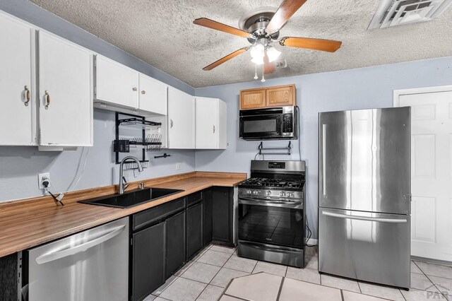 kitchen featuring a textured ceiling, stainless steel appliances, a sink, visible vents, and white cabinets