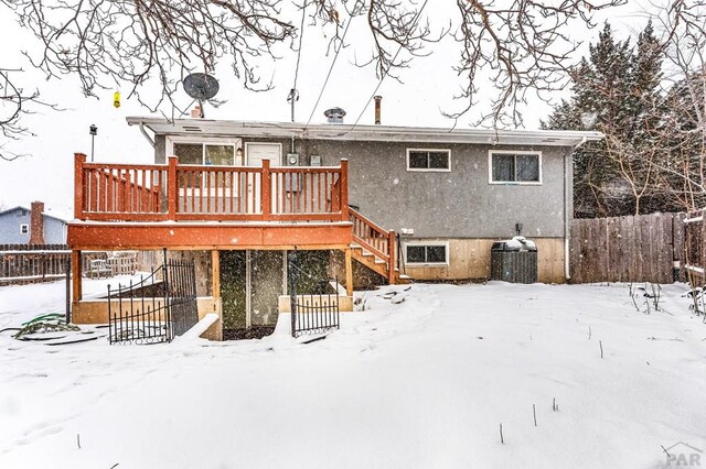 snow covered rear of property featuring fence and a wooden deck