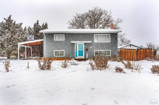 raised ranch with fence and stucco siding