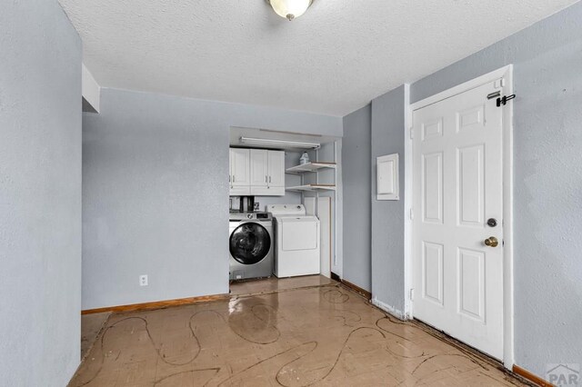 laundry room featuring cabinet space, baseboards, a textured ceiling, and independent washer and dryer