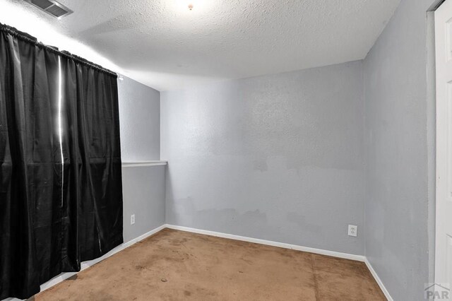 unfurnished room with baseboards, visible vents, and a textured ceiling