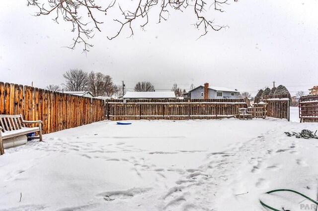 yard covered in snow with a fenced backyard