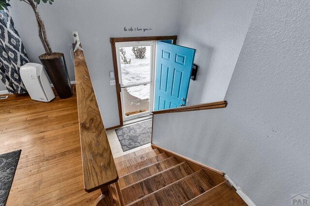 entryway featuring a textured wall, wood finished floors, and baseboards