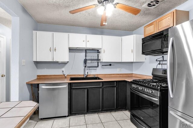 kitchen with dark cabinets, white cabinetry, stainless steel appliances, and a sink