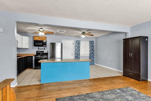 kitchen with white cabinetry, light tile patterned floors, visible vents, and appliances with stainless steel finishes