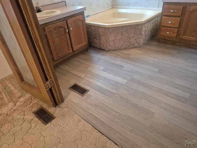 1106 10th St, Las Animas, CO 81054 - full bath featuring vanity, a garden tub, and wood finished floors