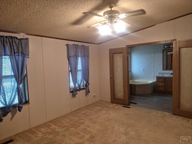 1106 10th St, Las Animas, CO 81054 - unfurnished bedroom with a textured ceiling, ornamental molding, carpet, a ceiling fan, and connected bathroom