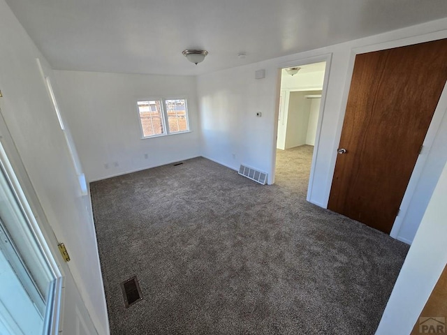 spare room featuring dark colored carpet and visible vents