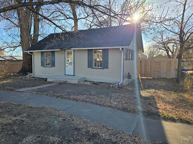 bungalow-style house with roof with shingles and fence