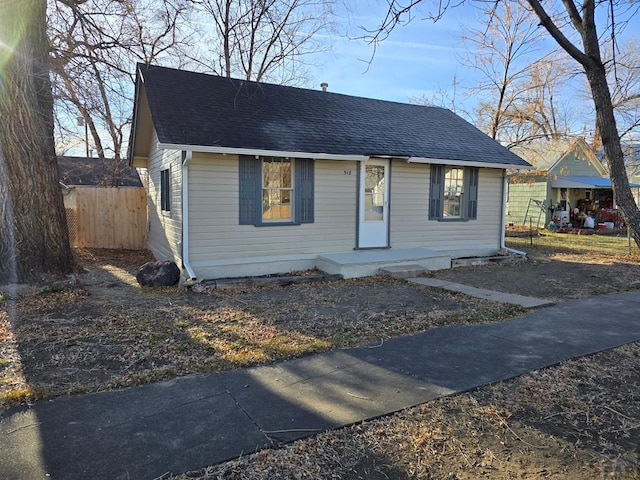 bungalow with a shingled roof and fence