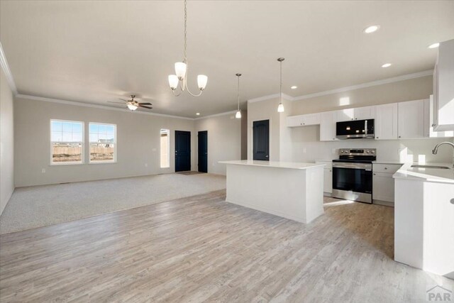 kitchen with stainless steel appliances, white cabinetry, open floor plan, light countertops, and a center island