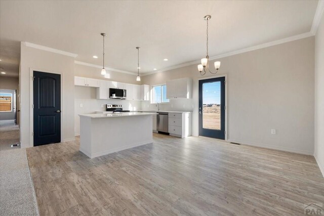 kitchen with white cabinets, appliances with stainless steel finishes, a center island, light countertops, and pendant lighting