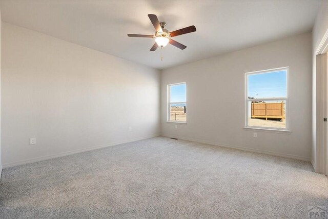 unfurnished room featuring light carpet, ceiling fan, and baseboards