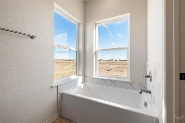 bathroom with a textured wall and a bath