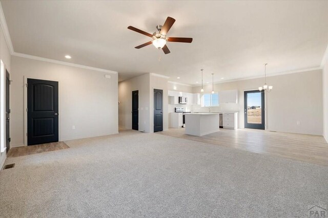 unfurnished living room featuring visible vents, light colored carpet, ornamental molding, ceiling fan with notable chandelier, and recessed lighting