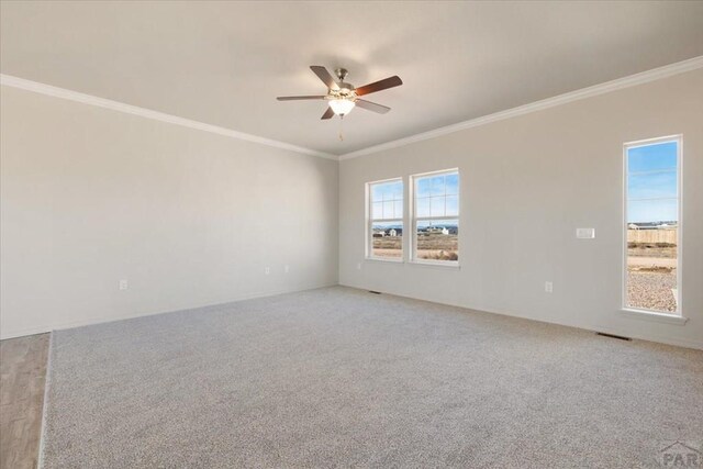 empty room featuring light carpet, ceiling fan, visible vents, and ornamental molding