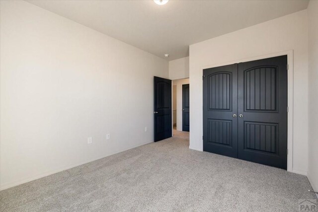 unfurnished bedroom featuring a closet and light colored carpet