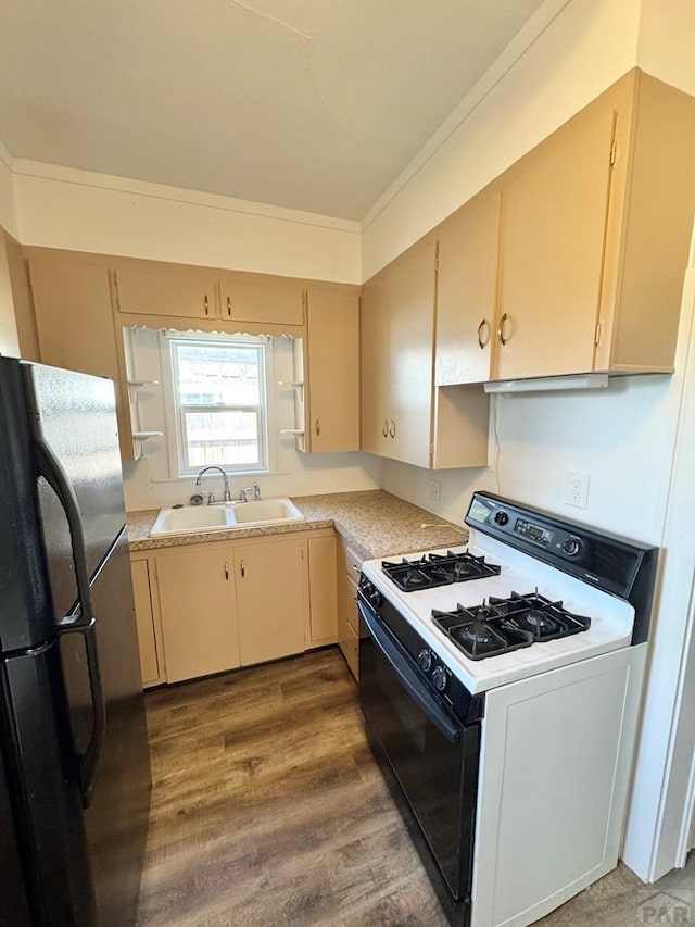 kitchen featuring light countertops, freestanding refrigerator, gas range gas stove, and a sink