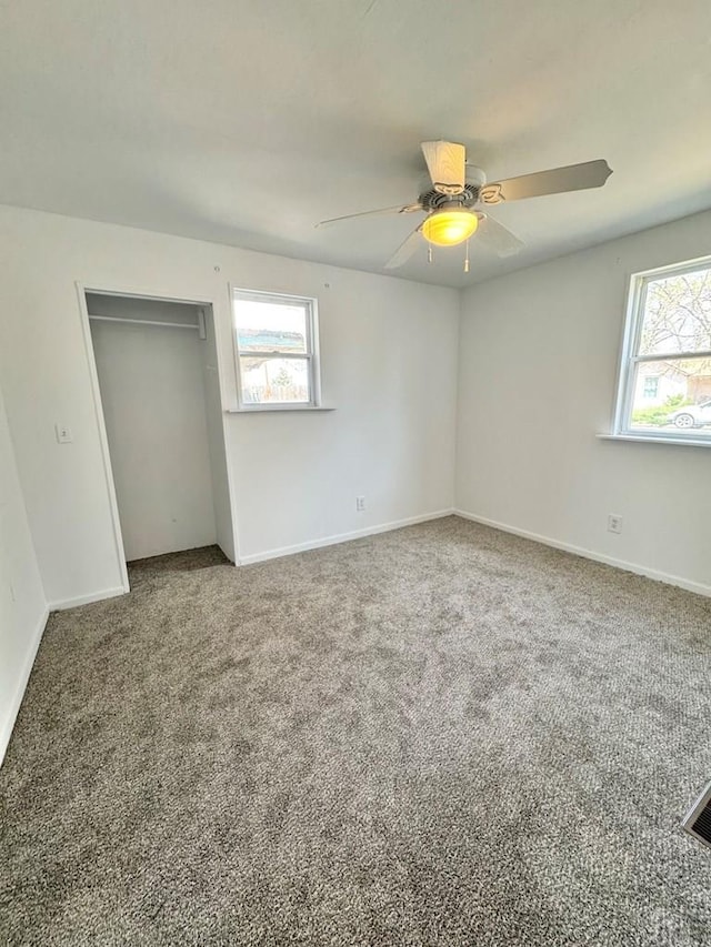 carpeted empty room featuring baseboards, a wealth of natural light, and ceiling fan