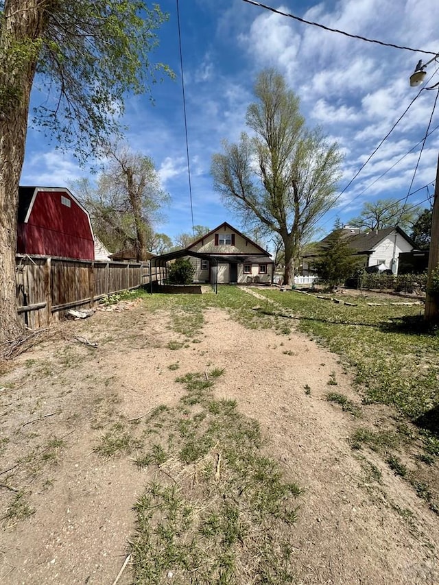 view of yard with an outdoor structure, fence, a barn, and dirt driveway