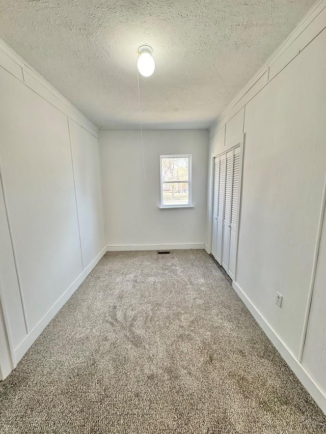 unfurnished bedroom with a closet, a textured ceiling, and light colored carpet