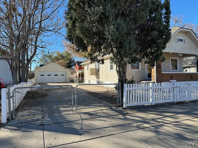 view of front facade featuring a garage, a fenced front yard, an outbuilding, and stucco siding