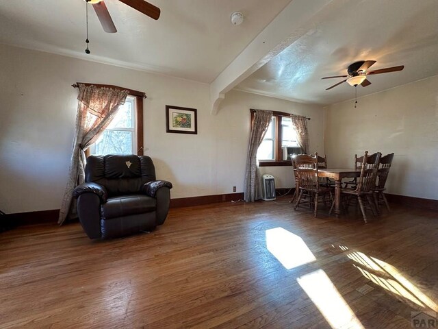 living area with dark wood-style floors, ceiling fan, and baseboards