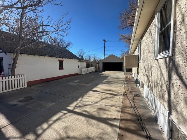 view of side of property with a garage, an outdoor structure, fence, and stucco siding