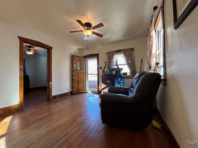 living room featuring ceiling fan, dark wood-style flooring, and baseboards