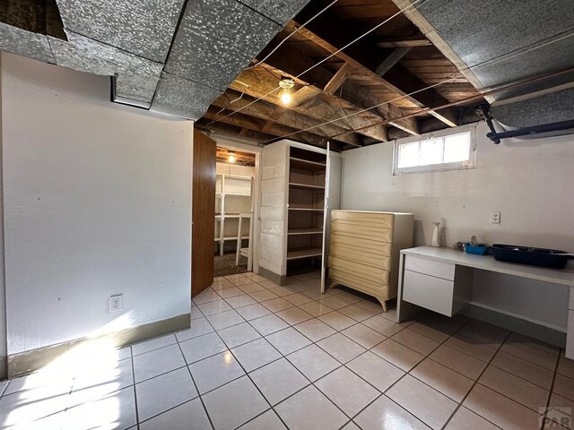 basement featuring baseboards and tile patterned floors