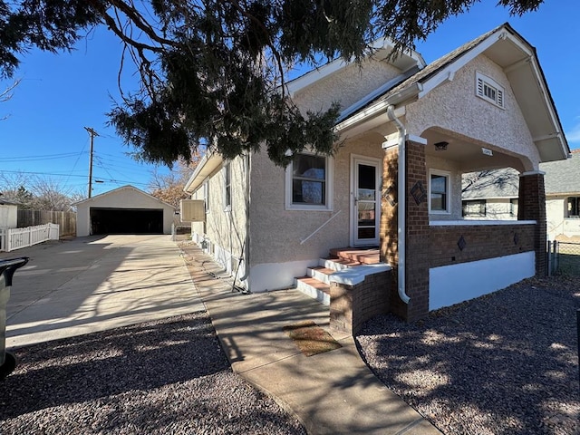 view of front of house featuring stucco siding, fence, and an outdoor structure