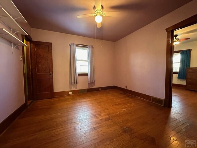 unfurnished room featuring dark wood finished floors, a ceiling fan, and baseboards