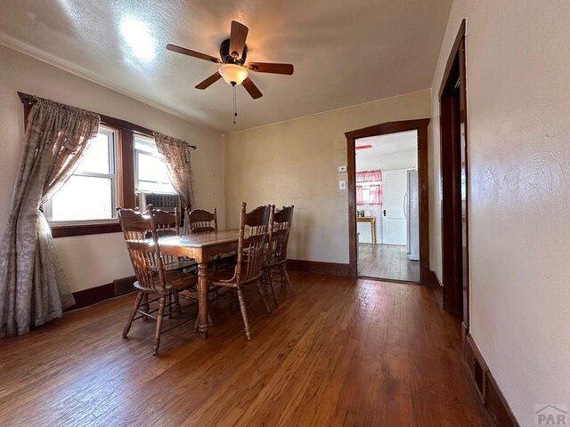 dining space with visible vents, baseboards, ceiling fan, wood finished floors, and cooling unit