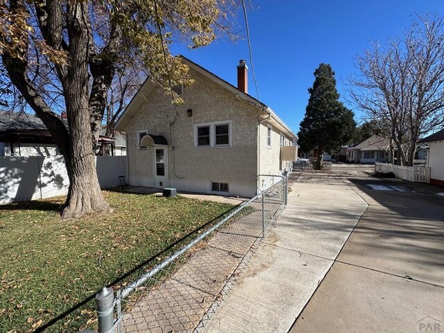 exterior space with fence, a chimney, a front lawn, and stucco siding