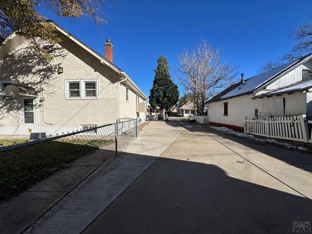 view of home's exterior featuring a patio area, fence, a chimney, and stucco siding