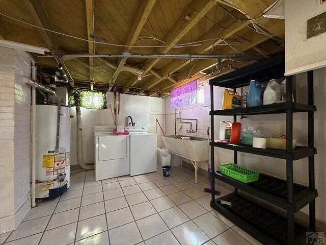 below grade area featuring tile patterned flooring, gas water heater, a healthy amount of sunlight, and washing machine and clothes dryer