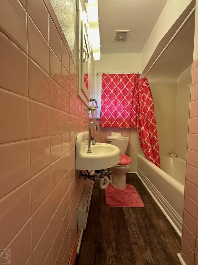 full bath featuring visible vents, toilet, shower / tub combo, a sink, and wood finished floors