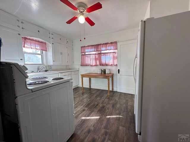 kitchen featuring white appliances, a sink, white cabinetry, light countertops, and dark wood-style floors