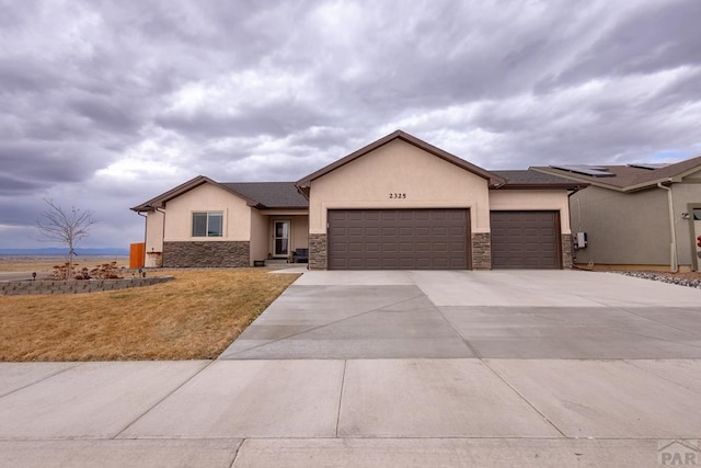 view of front of home with a garage, stone siding, driveway, stucco siding, and a front yard