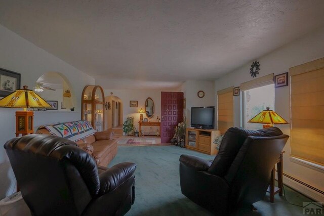 living area with a baseboard heating unit, arched walkways, and a textured ceiling