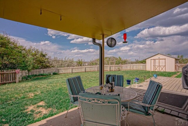 view of patio featuring a storage shed, a fenced backyard, outdoor dining space, and an outdoor structure