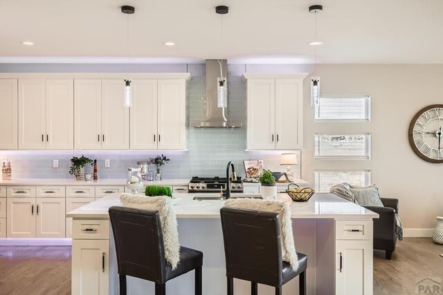 kitchen featuring light countertops, wall chimney range hood, and pendant lighting