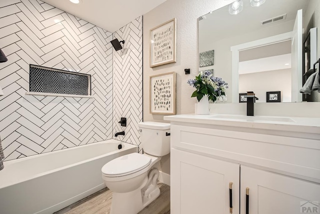 bathroom with visible vents, toilet, wood finished floors,  shower combination, and vanity